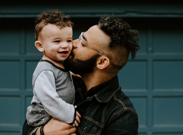 Adult holding child and giving a kiss on the cheek