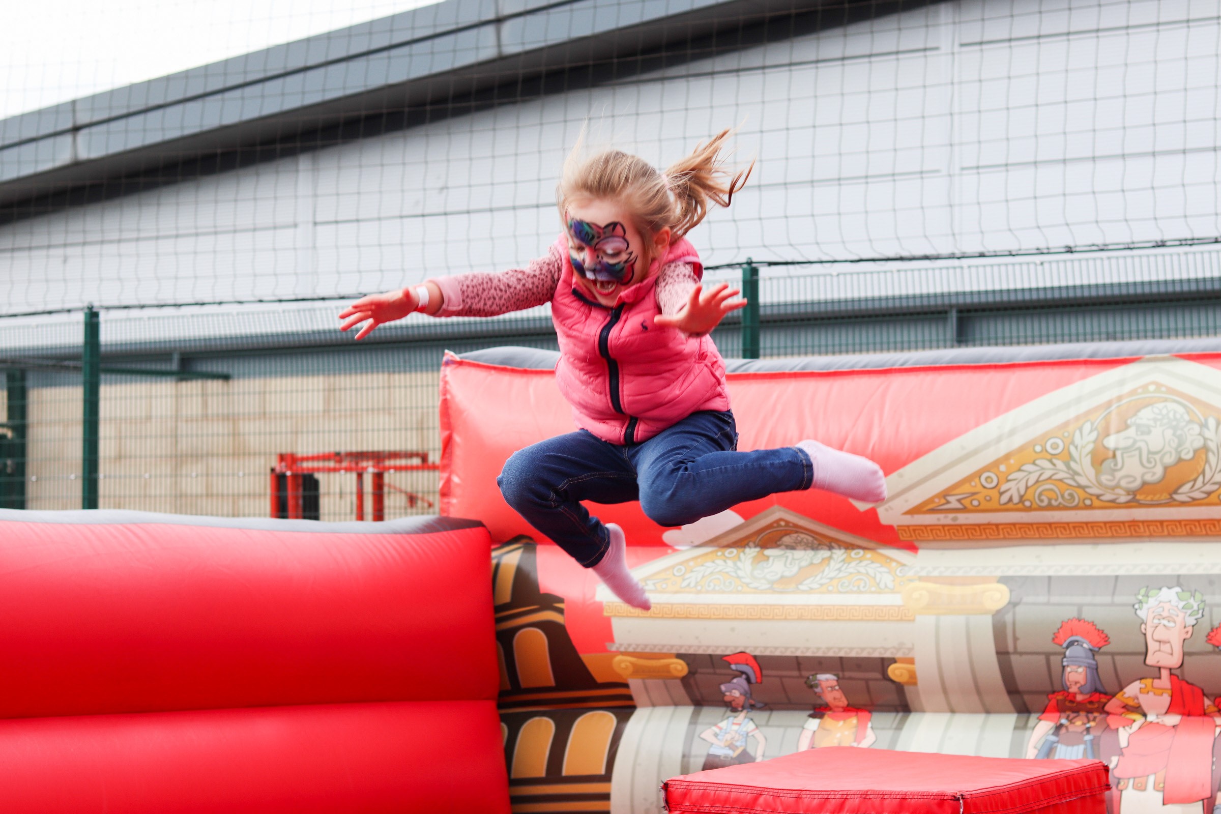 Young Girl jumping on a bouncy castle with face paint on